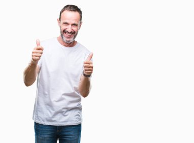Orta yaş ağarmış komuta sizde izole arka plan başarı işareti el ile pozitif jest yapıyor üzerinde beyaz t-shirt giyen başparmak gülümseyen ve mutlu. Neşeli bir ifadeyle, kazanan jest kameraya bakıyor.