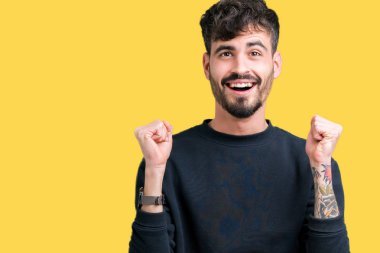 İzole arka plan kutlama üzerinde genç yakışıklı adam şaşırttı ve başarı için kaldırdı kollarını açarak hayret ve gözleri açık. Kazanan kavramı.