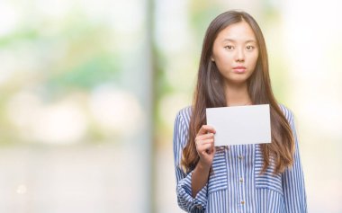 Acımak yüz ciddi düşünüyorum üstünde kendine güvenen bir ifade ile izole arka plan üzerinde boş kartı tutan Genç Asyalı kadın