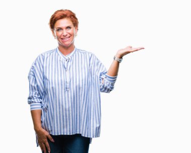 Atrractive üst düzey beyaz Kızıl saçlı kadın neşeli sunulması ve kameraya bakarak avucunun ile işaret gülümseyen izole arka plan.