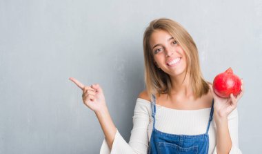 Grunge gri duvar nar çok mutlu el ve parmak ile tarafına işaret tutan güzel genç kadın