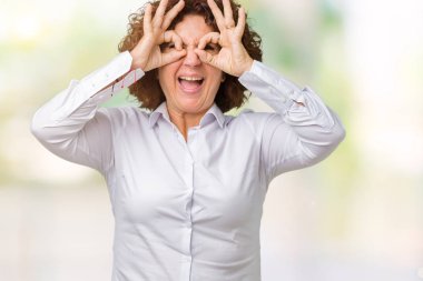 Güzel orta ager üst düzey businees kadın dilini, parmaklarının arasından baktığını yapışmasını dürbün gibi ok jest yapıyor izole arka plan yüzünden. Deli ifade.