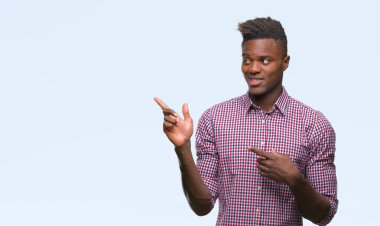 Gülümseyen ve iki elleri ve parmakları ile tarafına işaret kamera bakarak izole arka plan üzerinde genç Afro-Amerikan adam.