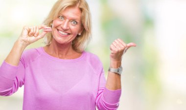 Orta yaş sarışın kadın işaret ve başparmak kadar mutlu yüz gülümseyen tarafı ile gösteren izole arka plan üzerinde pembe macaron bisküvi yediğine