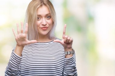 Genç Sarışın kadın gösterilen ve parmakları ile işaret izole arka plan yüzünden kendinden emin ve mutlu gülümseyerek süre yedi numara.