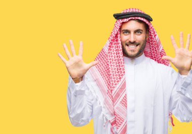 Keffiyeh üzerinde giyen genç yakışıklı adam arka plan gösteren izole ve parmakları ile işaret kendinden emin ve mutlu gülümseyerek süre on numara.