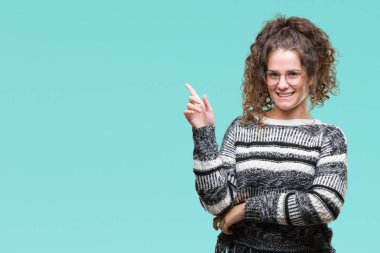 Kameraya bakarak yan el ve parmak ile işaret yüzünde kocaman bir gülümseme ile izole arka plan üzerinde gözlük güzel esmer kıvırcık saçlı Genç kız.