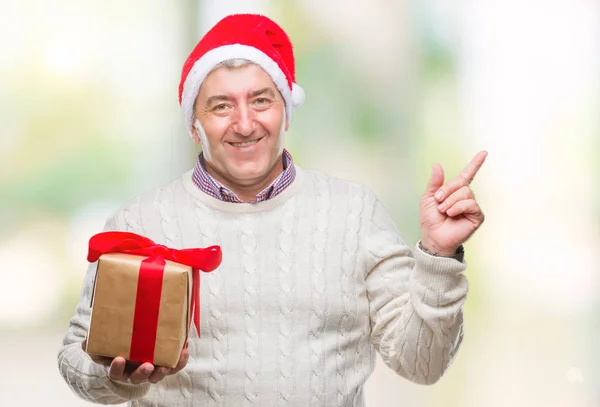 Hombre Mayor Guapo Usando Sombrero Navidad Sosteniendo Regalo Sobre Fondo —  Fotos de Stock