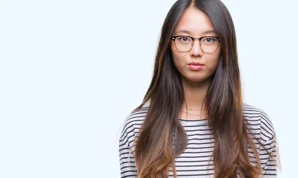 若いアジア女性の眼鏡を顔に真剣な表情で孤立した背景の上 シンプルで自然なカメラを見てください — ストック写真