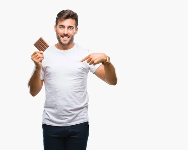 Young Handsome Man Eating Chocolate Bar Isolated Background Surprise Face — Stock Photo, Image