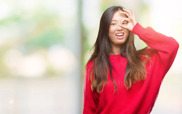 年轻的亚洲妇女穿着冬季毛衣在孤立的背景下做 手势用手微笑 眼睛看通过手指与愉快的面孔 — 图库照片