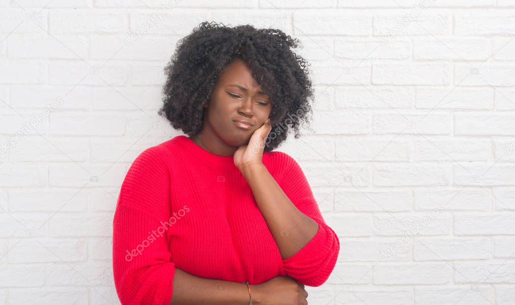 Young african american plus size woman over white brick wall thinking looking tired and bored with depression problems with crossed arms.