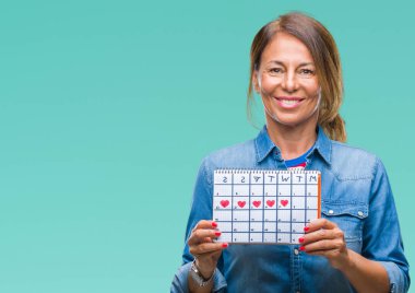 Adet takvim izole arka plan üzerinde duran ve diş gösterilen kendine güvenen bir gülümsemeyle gülümseyerek mutlu bir yüz tutan orta yaş üst düzey İspanyol kadın