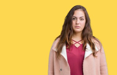 Artı boyutu genç kadın güzel üzerinde kış palto giyiyor arka plan gevşek yüzünde ciddi bir ifade ile izole. Basit ve doğal kameraya bakıyor.