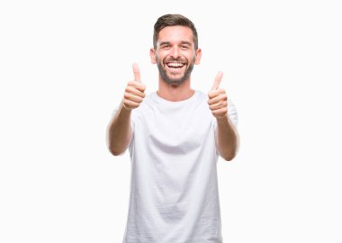 Yakışıklı delikanlı izole arka plan başarı işareti el ile pozitif jest yapıyor üzerinde başparmak gülümseyen ve mutlu. Neşeli bir ifadeyle, kazanan jest kameraya bakıyor.