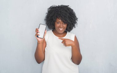 Gri grunge genç Afro-Amerikan kadın duvar manifatura smartphone el ve parmak ile işaret çok mutlu kullanarak bir ileti