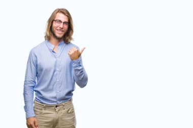 Genç yakışıklı adam uzun saçlı gözlüklü seyir ve başparmak yanında yukarıyı mutlu yüz ile gülümseyen izole arka plan üzerinde.