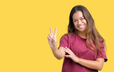 Genç güzel esmer kadın mutlu yüz zafer işareti yaparken kameraya göz kırpıyor ile gülümseyen izole arka plan yüzünden. İki numaralı.