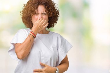 Beyaz t-shirt giyen bir şey pis ve iğrenç kokulu izole arka plan, dayanılmaz koku, holding nefes burun parmaklar ile güzel orta ager kadın kıdemli. Kötü kokuyor kavramı.