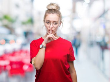 Dudaklarında parmak ile sessiz olmanı izole arka plan üzerinde gözlüklü sarışın genç kadın. Sessizlik ve gizli kavramı.