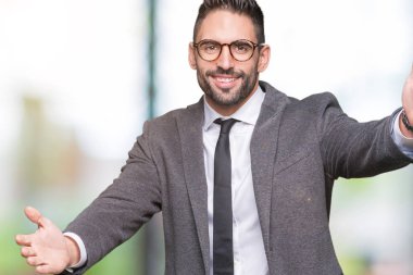 Genç yakışıklı iş adamı sarılmak için kollarını açarak gülümseyerek kameraya bakarak izole arka plan üzerinde. Neşeli ifade kucaklayan mutluluk.