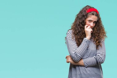 Güzel esmer kıvırcık saçlı Genç kız stresli ve gergin elle çivi ısırma ağzına bakarak izole arka plan üzerinde çizgili kazak giyiyor. Anksiyete sorunu.