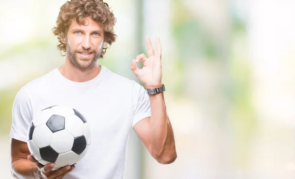 優秀なシンボルの指で サインをして孤立した背景にサッカー サッカー ボールを保持しているハンサムなヒスパニック系男性モデル — ストック写真