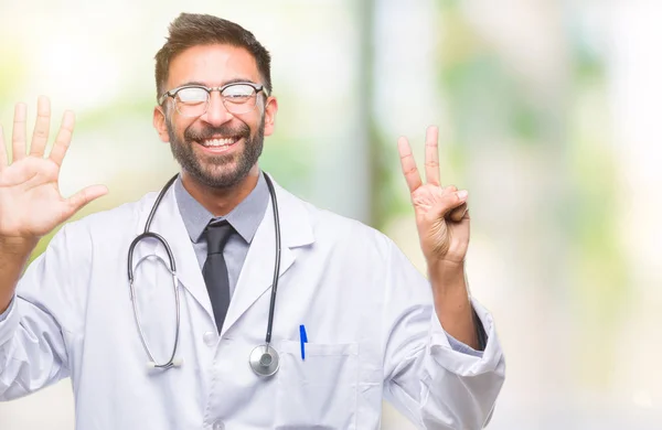 成人拉美裔医生男子在孤立的背景显示和指向与手指数字七同时微笑自信和快乐 — 图库照片