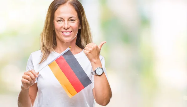 指していると幸せそうな顔を笑顔で側まで親指で示す分離の背景にドイツの国旗を保持している中年のヒスパニック系女性 — ストック写真