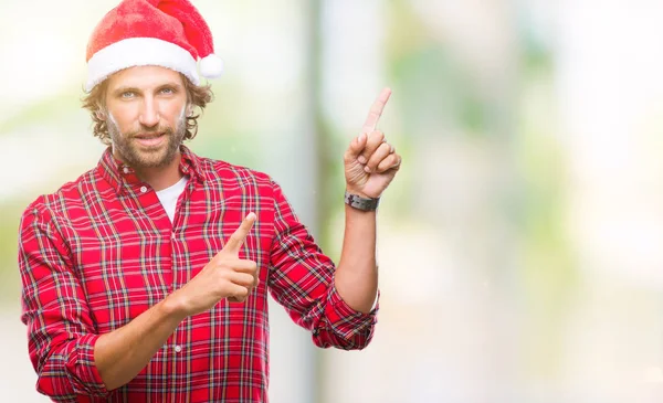 英俊的拉美裔男子模型穿着圣诞老人圣诞节在孤立的背景微笑和看着相机指着两个手和手指到一边 — 图库照片