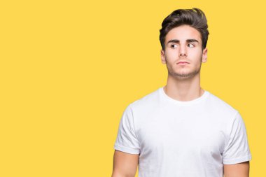 Görünümlü yan ve dik dik bakma uzağa düşünce gülümseyen izole arka plan üzerinde beyaz t-shirt giyen genç yakışıklı adam.