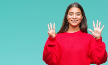 Genç güzel Arap kadın giyiyor kış kazak gösterilen ve parmakları ile işaret izole arka plan üzerinde kendinden emin ve mutlu gülümseyerek süre sekiz numara.