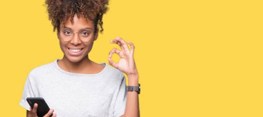 Parmak, mükemmel sembolü ile ok işareti yapıyor izole arka plan üzerinde akıllı telefon kullanan genç Afro-Amerikan kadın