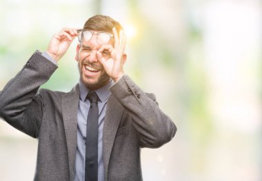 Genç yakışıklı iş adamı gülümseyen, parmakları ile mutlu yüz üzerinden seyir göz el ile ok jest yapıyor izole arka plan üzerinde.