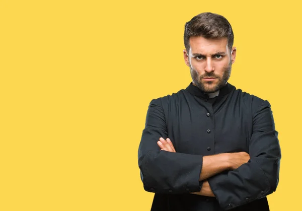 Young catholic christian priest man over isolated background skeptic and nervous, disapproving expression on face with crossed arms. Negative person.