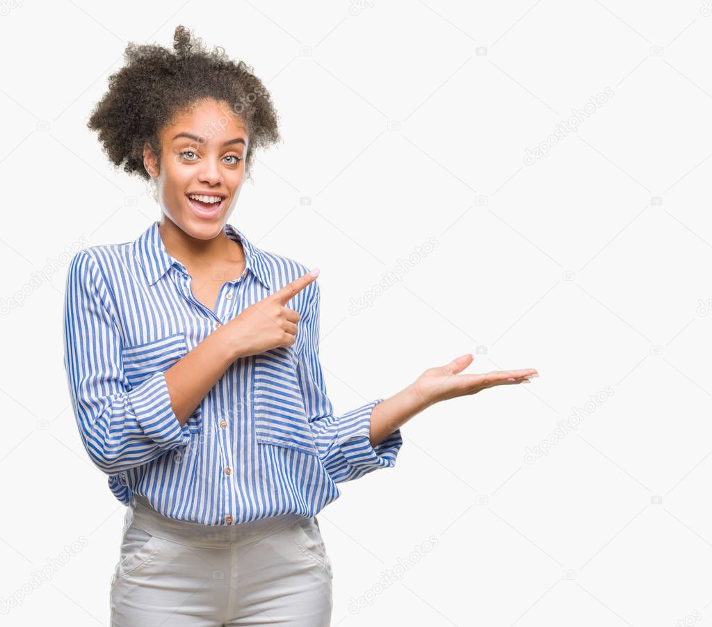 Young afro american woman over isolated background amazed and smiling to the camera while presenting with hand and pointing with finger.