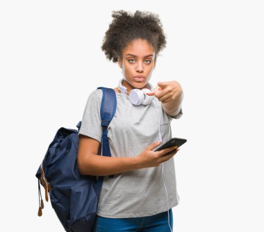 Genç güzel afro Amerikan öğrenci kadın sırt çantası holding kamera ve size parmak ile işaret arka plan izole, el işareti, pozitif ve kendinden emin bir jest ön