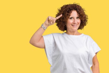 Beyaz t-shirt üzerinde izole giyen güzel orta ager üst düzey kadın arka plan bir parmak, harika bir fikir ya da düşünce, iyi hafıza ile baş gösteren gülen
