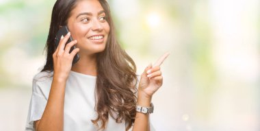 Genç güzel Arap kadın telefonda izole arka plan üzerinde çok el ve parmak ile tarafına işaret mutlu söz