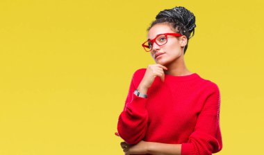 Genç kazak giyen Afro-Amerikan kız saç örgülü ve gözlük el ile izole arka plan üzerinde soru, dalgın ifade düşünmeye çene. Düşünceli yüzüyle gülümsüyor. Şüphe kavramı.