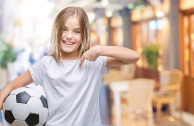 Sürpriz yüz işaret parmağı kendini izole arka plan üzerinde futbol futbol topu tutan genç güzel kız