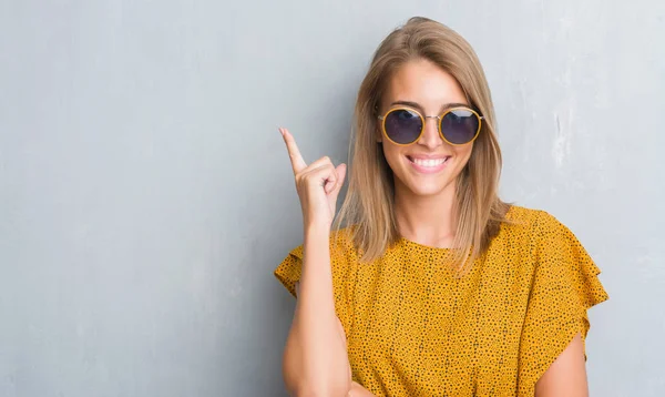 Hermosa Mujer Joven Pie Sobre Pared Gris Grunge Usando Gafas —  Fotos de Stock