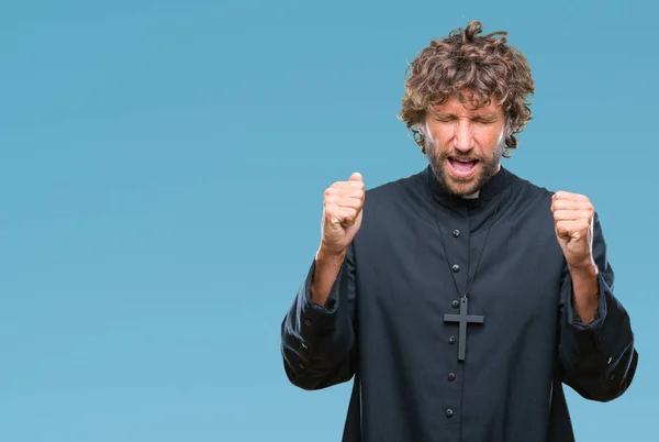 stock image Handsome hispanic catholic priest man over isolated background excited for success with arms raised celebrating victory smiling. Winner concept.