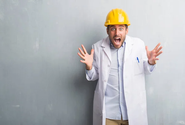 Guapo Joven Ingeniero Hombre Sobre Gris Grunge Pared Usando Casco — Foto de Stock