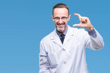 İzole arka plan gülümseyen ve boyutu işaret parmaklı ararken ve kamera işi el ile kendinden emin eller üzerinde beyaz önlük giyen orta yaş üst düzey ağarmış profesyonel adam. Ölçü kavramı.