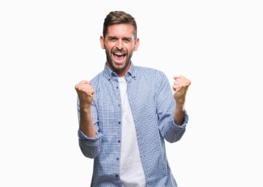 Gülümseyen ve başarı için çığlık çok mutlu ve heyecanlı kaldırdı, silah ile kazanan jest yapıyor izole arka plan üzerinde beyaz t-shirt giyen genç yakışıklı adam. Kutlama kavramı.