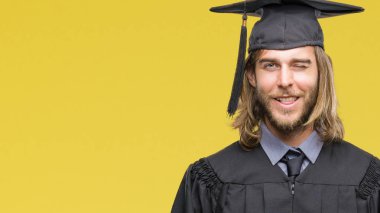 Genç yakışıklı adam uzun saçlı seksi bir ifadeyle, neşeli ve mutlu yüzünü kameraya bakarak göz kırpıyor izole arka plan üzerinde mezun oldu.