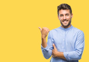 Yakışıklı delikanlı arıyor ve başparmak yanında yukarıyı mutlu yüz ile gülümseyen izole arka plan üzerinde.