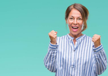 İzole arka plan kutlama üzerinde orta yaş İspanyol kadın kıdemli şaşırttı ve başarı için kaldırdı kollarını açarak hayret ve gözleri açık. Kazanan kavramı.