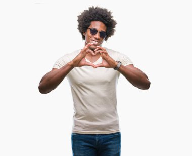 Afro Amerikalı adam aşık kalp simgesi ve elleriyle şekil gösteren gülümseyen izole arka plan üzerinde güneş gözlüğü takıyor. Romantik kavramı.